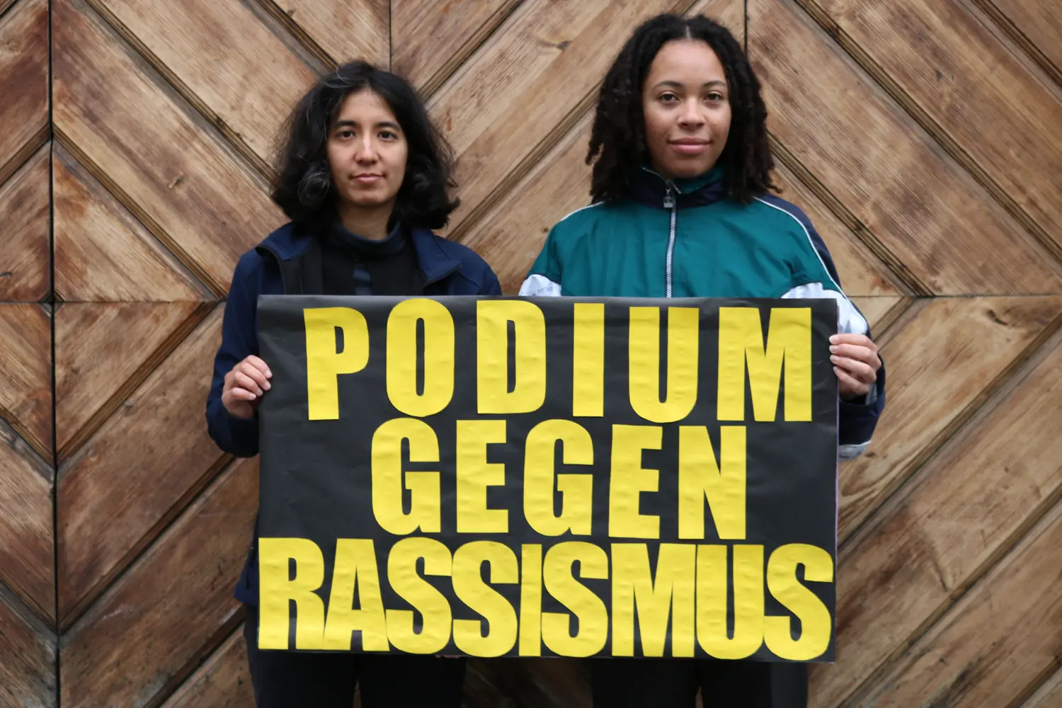 two people of color with a poster agains racism photo by afro-asian institute salzburg